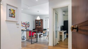 Puerta abierta que da a una sala de estar con comedor, un armario de madera y un televisor.