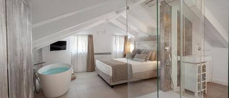 A modern bedroom with a glass shower enclosure, a large bed, and a bathtub.