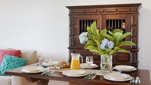 A dining table set with plates, glasses, a pitcher of orange juice, and a vase with flowers.