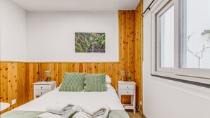 A bedroom with a bed, two nightstands, a window, and a wall-mounted picture.