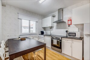 Uma cozinha moderna com armários brancos, forno embutido, micro-ondas e janela.