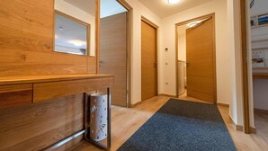 Un couloir avec des portes en bois, un miroir et une poubelle.