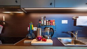 Une cuisine moderne dotée d’un évier en acier inoxydable, d’une planche à découper avec des légumes et d’un porte-épices.