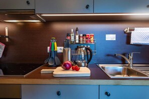 Une cuisine moderne dotée d’un évier en acier inoxydable, d’une planche à découper avec des légumes et d’un porte-épices.