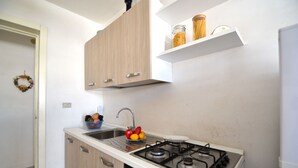 Una cocina con estufa a gas, un lavaplatos, armarios de madera y un frutero.