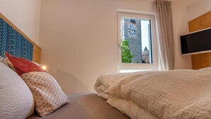 A bedroom with a bed, pillows, a window, and a TV. - Holiday Apartment "Gass B" with Mountain View, Private Terrace and Wi-Fi (Laion)