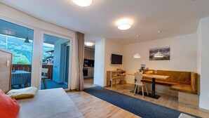 A modern interior with a sofa, dining area, and a view through a glass door. - Holiday Apartment "Gass B" with Mountain View, Private Terrace and Wi-Fi (Laion)