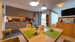A modern kitchen with a dining area, wooden cabinets, a microwave, and a flat-screen TV. - Holiday Apartment "Gass B" with Mountain View, Private Terrace and Wi-Fi (Laion)