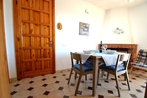 Een eethoek met een houten deur, een tafel met stoelen, een open haard en een muur met foto's.