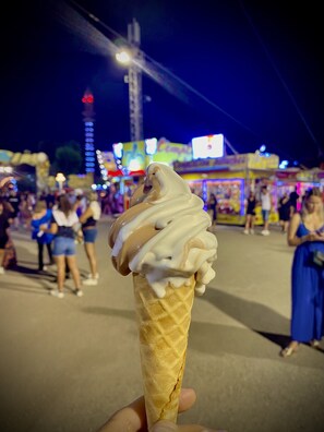 A hand holding a waffle cone with a scoop of ice cream.