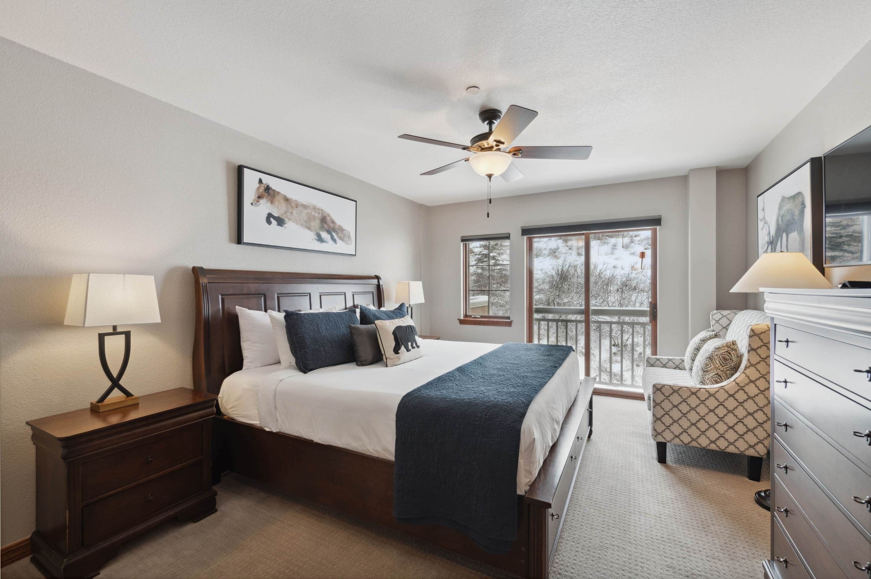 A bedroom with a bed, nightstand, dresser, and a balcony with a view.