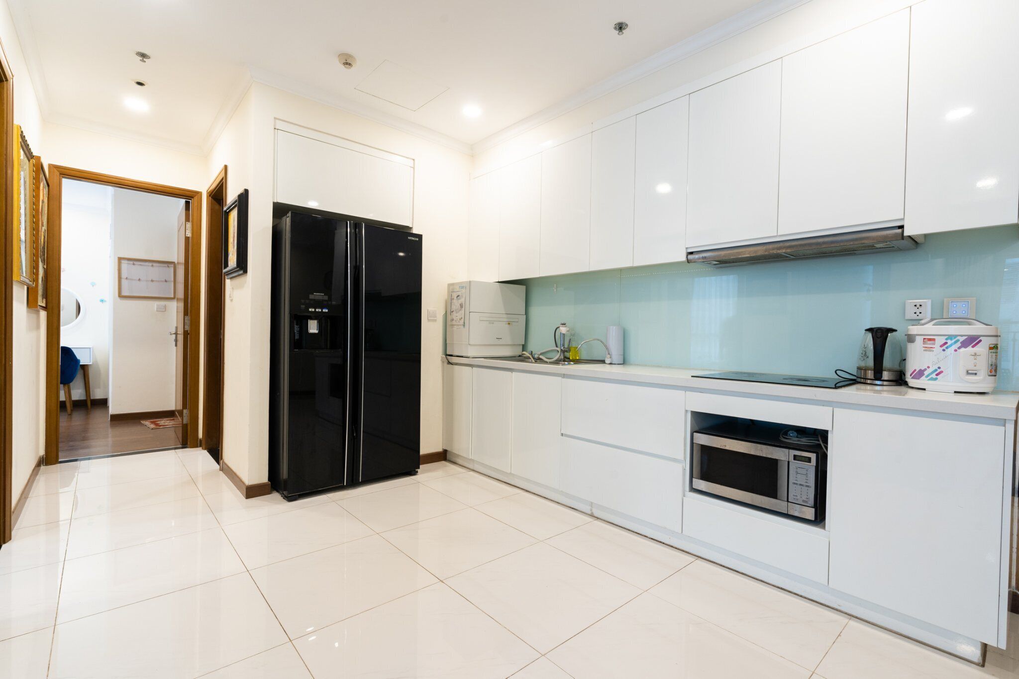 A modern kitchen with white cabinets, a black refrigerator, a microwave, and a coffee maker.