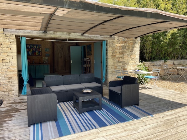 An outdoor seating area with wicker furniture and a striped rug.