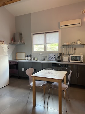 A modern kitchen with a dining table, chairs, a refrigerator, stove, sink, and various kitchen appliances.