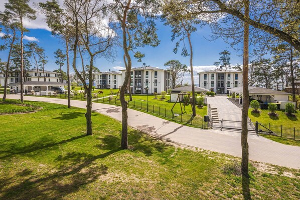A residential area with multiple two-story houses, a paved walkway, and a fenced lawn.