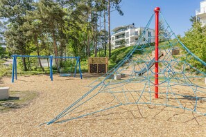 A playground with climbing structures, swings, and a wooden playhouse. - Hochwertiges Appartement in Ruhiger Lage, mit Terrasse, Kostenfreier Sauna und S (Zirchow)