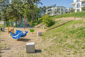 A playground with a blue whale swing set, a slide, and a climbing structure.