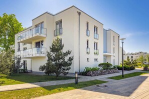 A modern apartment building with balconies, a paved walkway, and a well-maintained lawn. - Hochwertiges Appartement in Ruhiger Lage, mit Terrasse, Kostenfreier Sauna und S (Zirchow)
