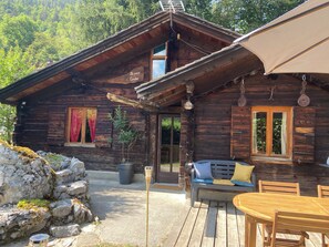 Eine rustikale Holzhütte mit Veranda, einem Esstisch und einer Couch.