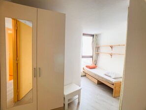 Une chambre avec un lit superposé, une petite table blanche et une armoire.
