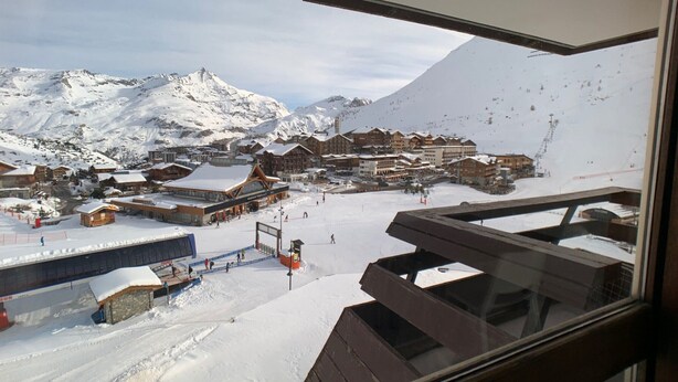 A snow-covered mountain town with wooden buildings and a ski slope.