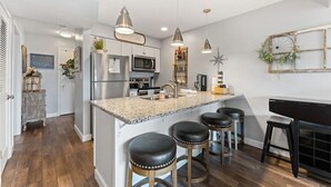 A modern kitchen with granite countertops, stainless steel appliances, and a central island with bar stools. - Cozy Branson Condo, +Free Tickets + Walk-In available (Reeds Spring)