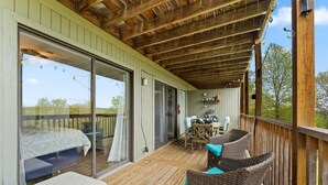 A covered outdoor area with wicker furniture, a table, and chairs. - Cozy Branson Condo, +Free Tickets + Walk-In available (Reeds Spring)