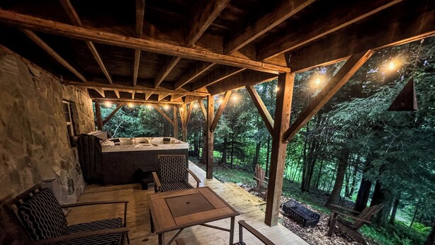 Une terrasse extérieure en bois, avec un mur en pierre, un jacuzzi et des sièges.