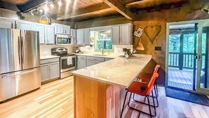 Une cuisine moderne dotée d’appareils électroménagers en acier inoxydable, de planchers en bois et d’un grand îlot central avec des tabourets de bar.