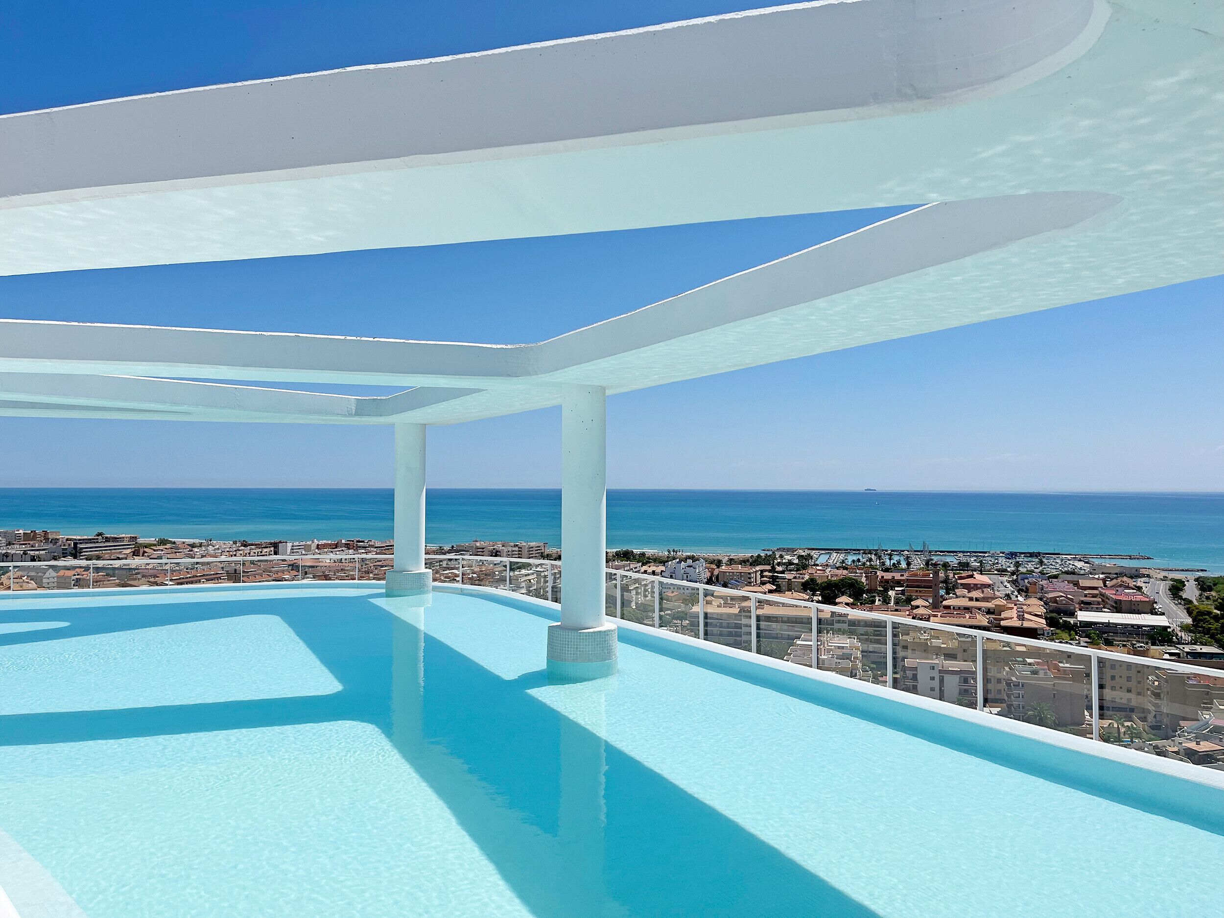 Una piscina en la azotea con vistas despejadas al océano y al paisaje urbano.