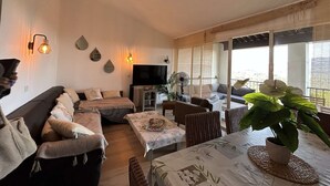 A cozy living room with a sofa, a TV, and a dining area with a table and chairs.