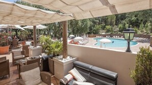 An outdoor patio area with seating, umbrellas, and a pool.