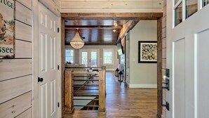 A wooden interior with a central staircase, large windows, and a hanging light fixture.