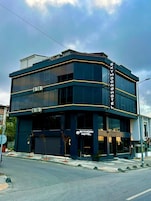 Un moderno edificio de hotel con fachada oscura y numerosas ventanas.