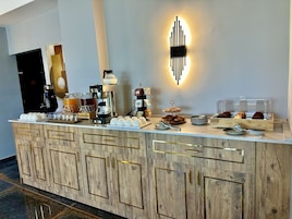 Una barra de desayuno con máquinas de café, té y pasteles.