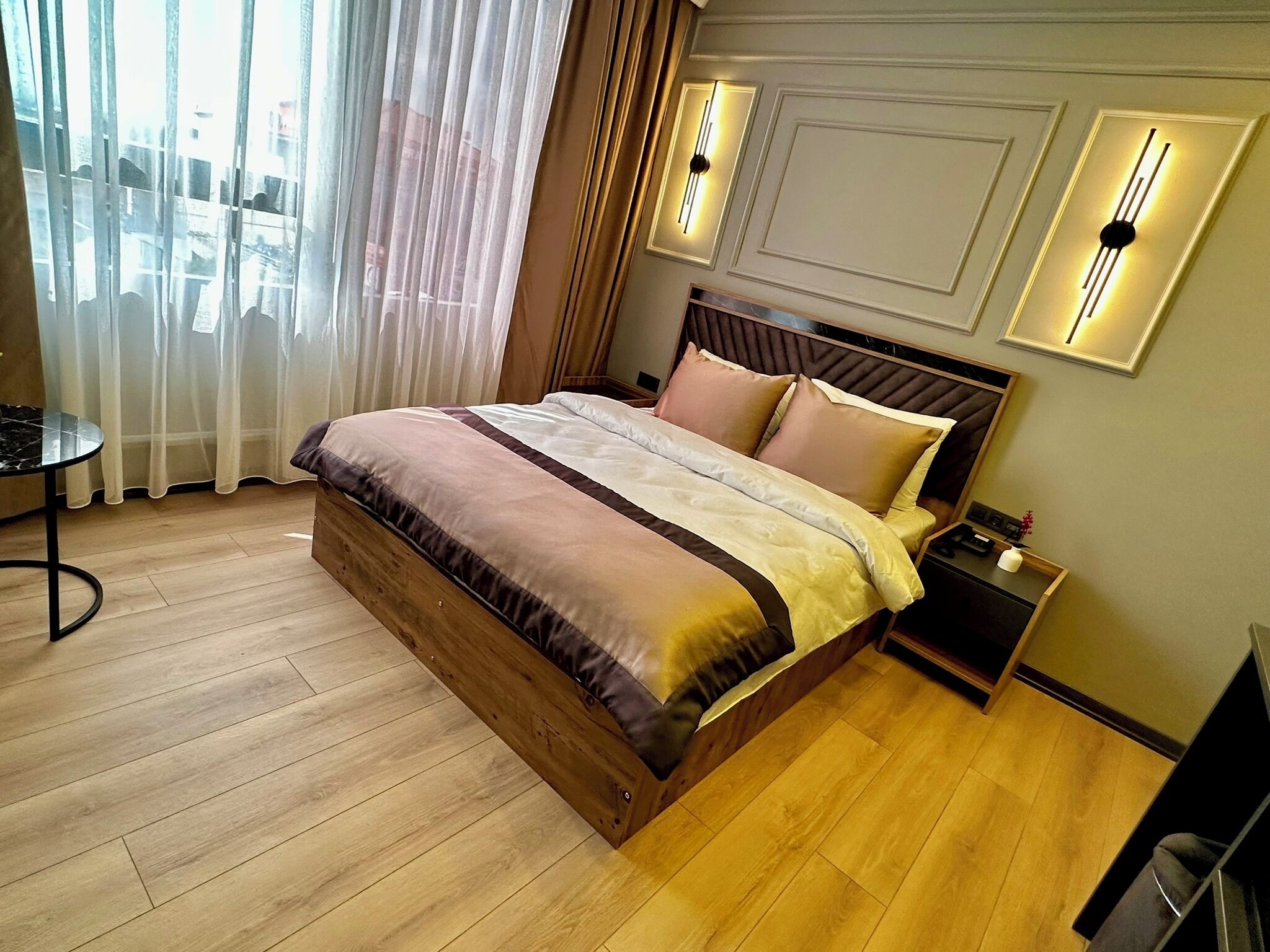 Quarto bem arrumado com uma cama de madeira, uma mesa de cabeceira e uma pequena mesa com uma cadeira.