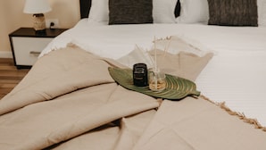 A neatly made bed with a green leaf and a bottle of lotion on the bedspread. - Agoston Galgon Holiday Apartments (Timisoara)