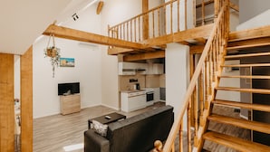 A spacious living area with a wooden staircase, a kitchen, and a sofa. - Agoston Galgon Holiday Apartments (Timisoara)