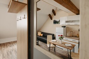 Una cocina moderna con armarios blancos, techo de madera y comedor con mesa para dos.