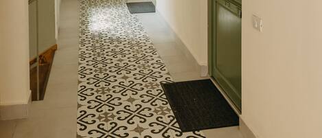 A hallway with patterned flooring, a green door, and a number 29 sign.