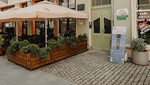 A building with a green door, a signboard, and a wooden bench with plants. - Agoston Galgon Holiday Apartments (Timisoara)