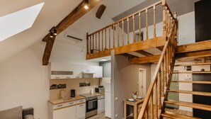 A modern kitchen with wooden beams, a dining area with a table and chairs, and a staircase leading to an upper level. - Agoston Galgon Holiday Apartments (Timisoara)
