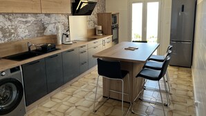A modern kitchen with a central island, bar stools, a washing machine, and a refrigerator. - Appartement à Tiuccia, les Pieds Dans L'eau, Climatisé, Wifi (Tiuccia)