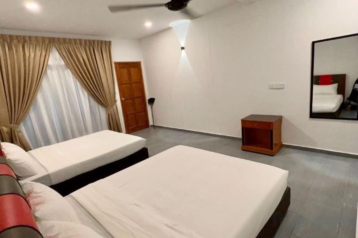 A hotel room with two beds, a ceiling fan, a small wooden nightstand, and a mirror on the wall.