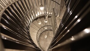 A spiral staircase with metal railings and hanging lights.