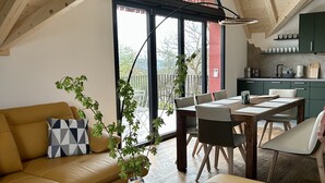 A modern loft with a high ceiling, a dining area, and a kitchen.