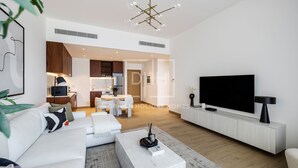 A modern living room with a white sofa, a flat-screen TV, and a minimalist design. - Full Sea View 1Bed Le Pont B1 in La Mer (Dubai)
