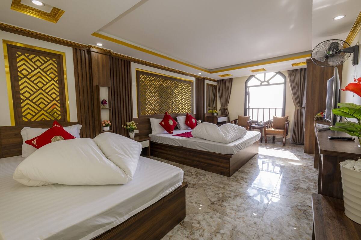 Een hotelkamer met twee bedden, een zithoek en een groot raam.