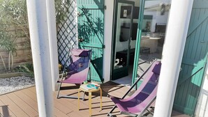 An outdoor seating area with two purple lounge chairs, a small table, and a glass door leading inside. - Cozy 4-Person Apartment Steps from Beach, BBQ, WiFi & Parking (Capbreton)