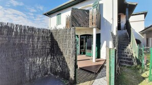 A two-story house with a wooden fence, a staircase, and a door with green shutters. - Cozy 4-Person Apartment Steps from Beach, BBQ, WiFi & Parking (Capbreton)